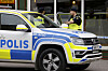 Polizei vor einer Kneipe in Sandviken, Schweden, neben einem Einsatzfahrzeug.