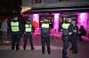 Polizisten stehen nachts vor einem Lokal mit Außenbestuhlung und kontrollieren den Bereich.