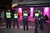 Polizisten stehen nachts vor einem Lokal mit Außenbestuhlung und kontrollieren den Bereich.