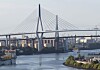 Große Schrägseilbrücke über einem Fluss mit Uferanlagen und Gebäuden im Hintergrund.