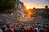 Zahlreiche Besucher verfolgen die Karl-May-Spiele im Kalkbergstadion vor dem Kalkberg bei Sonnenuntergang.