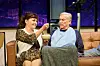 Simone Pfennig füttert den auf dem Sofa sitzenden Jochen Busse.