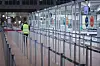 Eine Flughafenmitarbeiterin geht durch die geschlossene und menschenleere Sicherheitskontrolle im Flughafen Hamburg.