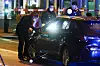 Polizisten mit Taschenlampen an einem Auto