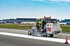 Markierungsfahrzeug mit Arbeitern auf der Startbahn am Flughafen während der Bahnsanierung.