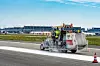 Markierungsfahrzeug mit Arbeitern auf der Startbahn am Flughafen während der Bahnsanierung.