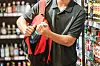 Mann steckt in einem Supermarkt eine Flasche mit Alkohol in einen Rucksack.