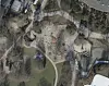 Luftaufnahme eines Spielplatzes mit Klettergerüsten, Sandflächen und Wegen im Park