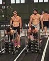 Männer schieben Gewichtsschlitten in einer Sporthalle vor einem MYPROTEIN-Banner.