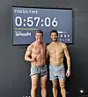 Zwei Athleten vor einer Finish-Time-Anzeige mit 0:57:06, Amazfit und Ironman Berlin sichtbar.