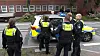 Mehrere Polizisten umringen einen Polizeiwagen mit Blaulicht vor einem Wohngebäude.