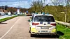 Polizeiwagen steht am Straßenrand neben einer Landstraße mit Bäumen und Verkehrsschildern.