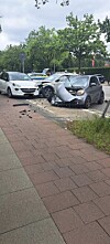 Zwei beschädigte Autos nach einem Zusammenstoß, Trümmerteile liegen auf Gehweg und Straße.