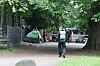 Polizeibeamtin geht auf einem Waldweg an Zelten und Fahrrädern in einem provisorischen Lager vorbei.