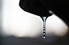 Ein Wassertropfen hängt an einem Hahn vor hellem, unscharfem Hintergrund.