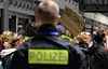 Demonstrierende vor Polizeikette, im Vordergrund ein Polizist mit „POLIZEI“ auf der Jacke.