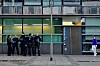 Mehrere Polizisten vor dem Eingang des 1. Reviers in Frankfurt, rechts eine Passantin vor dem Gebäude.