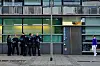 Mehrere Polizisten vor dem Eingang des 1. Reviers in Frankfurt, rechts eine Passantin vor dem Gebäude.