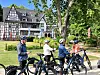 Mehrere Radfahrer stehen vor einer Fachwerkvilla am Parkweg.