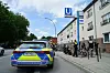 Polizeiauto vor Wohnhäusern, Beamte und Fahrräder an einer abgesperrten Straße.