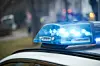 Polizeiwagen mit eingeschaltetem Blaulicht auf der Straße, im Hintergrund unscharfe Lichter.