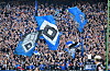 HSV-Fans schwenken blau-weiße Fahnen im dicht besetzten Stadion während des Spiels gegen SC Freiburg.