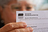 Seniorin hält ein Schreiben der Deutschen Rentenversicherung Berlin-Brandenburg in der Hand.