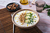Schale kalter Gurkensuppe mit Gurkenscheiben, Kräutern und Gewürzen auf dem Tisch.