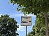 Schild zur Videokontrollzone im Parkbereich vor Bäumen und blauem Himmel.