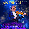 André Rieu spielt Geige auf einer blau beleuchteten Bühne vor seinem Orchester.
