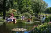 Wasserlauf im Park Planten un Blomen mit Grün, Blumen und Besuchern am Ufer.