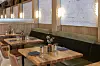 Gedeckte Holztische, gepolsterte Sitzbank und warme Wandlampen im Restaurant Deckman’s North at 3131 in San Diego.