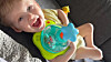 Baby auf einer Couch mit buntem Trinklernbecher und kleinem Stofftier