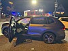 Beschädigter SUV mit offener Fahrertür auf nasser Straße bei Nacht, umgeben von Blaulicht und Einsatzfahrzeugen.