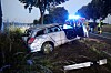 Beschädigter Kleinwagen im Graben, dahinter Einsatzfahrzeuge mit Blaulicht und Rettungskräfte an der Unfallstelle.