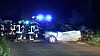 Verunglückter Pkw nach Frontalaufprall gegen Baum, Feuerwehr und Einsatzfahrzeuge bei Nacht am Straßenrand.