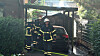 Feuerwehrleute vor verbranntem Auto im Holzcarport in Hamburg-Schnelsen nach Brand.