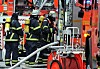 Feuerwehrleute löschen am Eppendorfer Baum einen Dachstuhlbrand, Schläuche und Einsatzfahrzeuge im Vordergrund.