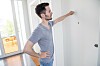 Mann klopft im hellen Hausflur einer Berliner Wohnanlage an eine Wohnungstür.