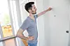 Mann klopft im hellen Hausflur einer Berliner Wohnanlage an eine Wohnungstür.