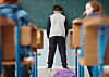 Ein Junge steht unglücklich an einer Schultafel. Die Schulbehörde plant Einschnitte bei Schulbegleitungen.