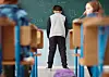 Ein Junge steht unglücklich an einer Schultafel. Die Schulbehörde plant Kürzungen bei Schulbegleitungen.