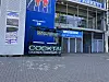 Geschlossene Ladenfront mit Cocktailschildern und Museumswerbung vor leerem Gehweg.