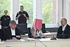 Mehrere Personen beraten an einem Konferenztisch in einem hellen Sitzungssaal.