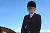 Person in dunkler Reituniform auf einem Pferd vor blauem Himmel.