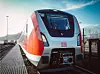 Roter und weißer DB-Zug steht am Bahnsteig neben einem Zaun.