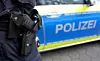 Polizeibeamter neben blau-weißem Einsatzfahrzeug mit „Polizei“-Schriftzug.
