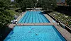 Badegäste im Kaifu-Bad in Hamburg liegen an Becken und Liegewiese, wenige schwimmen im Wasser.