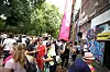 Menschenmenge steht vor graffitibedeckter Hausfassade und pinkem Banner an einer Straßenecke.