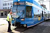 Blauer Straßenbahnzug der Bremer Straßenbahn an der Haltestelle, ein Mann in Warnweste steht davor.